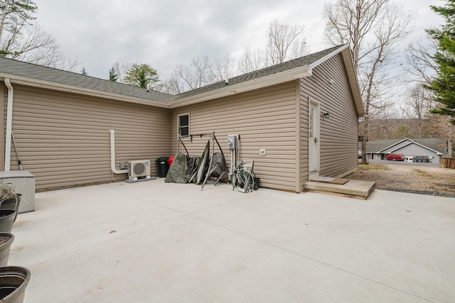 exterior space featuring a shingled roof, a patio area, and ac unit