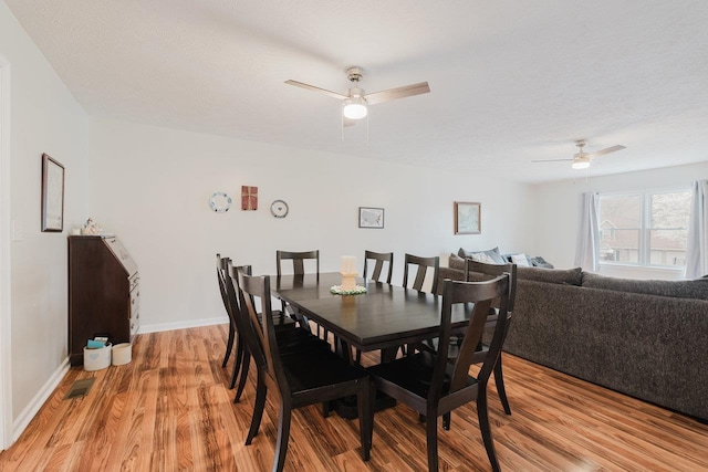 dining room with visible vents, light wood-style flooring, baseboards, and ceiling fan