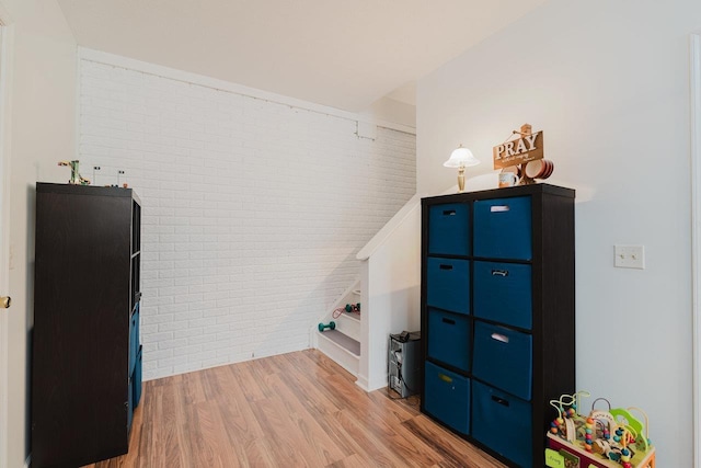 bonus room featuring brick wall and light wood-type flooring