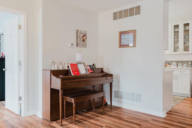 hallway featuring visible vents, light wood-style flooring, and baseboards