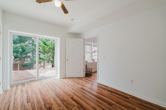 spare room featuring a wealth of natural light, baseboards, a ceiling fan, and wood finished floors