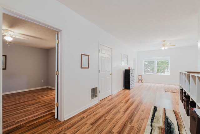 unfurnished living room with light wood finished floors, visible vents, and a ceiling fan