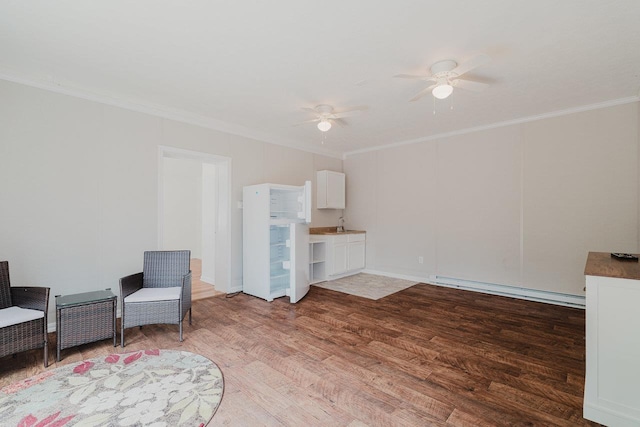 living area featuring crown molding, baseboard heating, ceiling fan, and wood finished floors