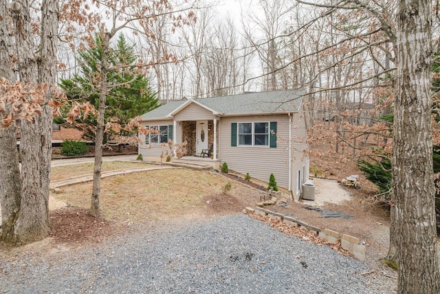 single story home featuring a shingled roof and gravel driveway