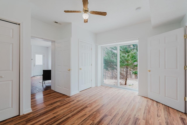 unfurnished bedroom with ceiling fan, access to outside, visible vents, and wood finished floors