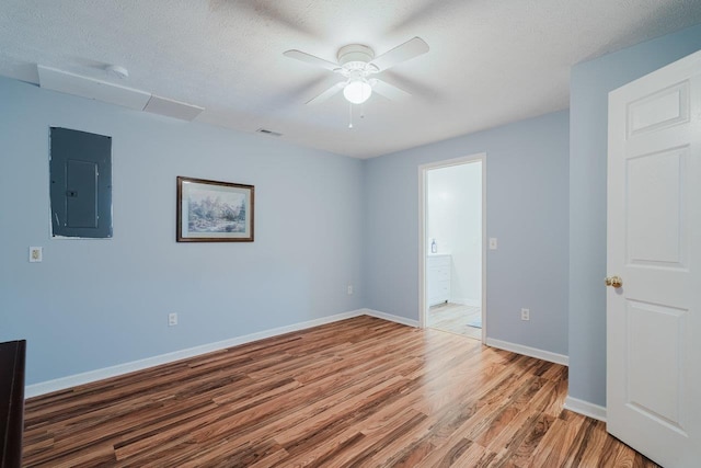 unfurnished room featuring electric panel, visible vents, ceiling fan, light wood-style flooring, and baseboards