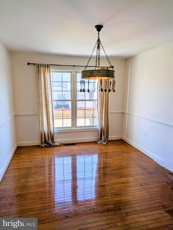 unfurnished dining area featuring a chandelier, hardwood / wood-style floors, and baseboards