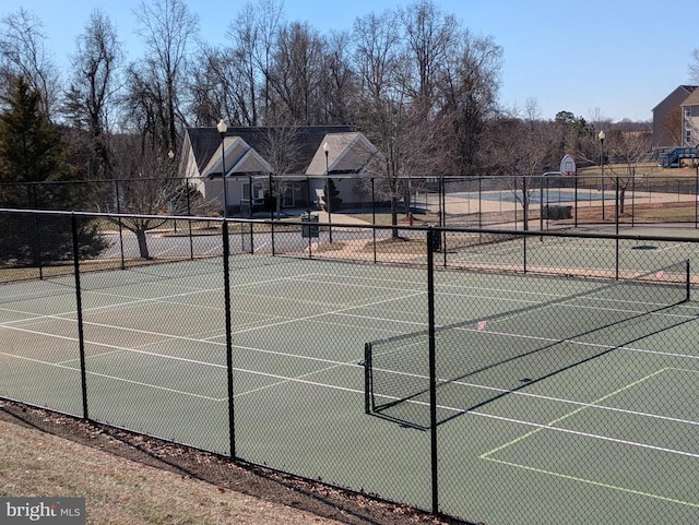 view of tennis court featuring fence and community basketball court