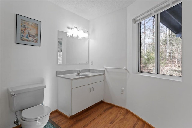 bathroom with vanity, toilet, a textured ceiling, and wood finished floors