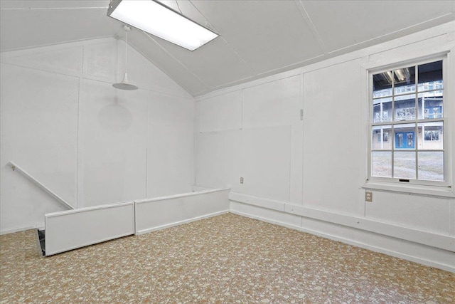 empty room featuring a decorative wall and lofted ceiling