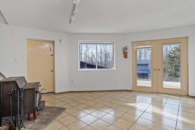 interior space with rail lighting, light tile patterned flooring, a wealth of natural light, and a wood stove