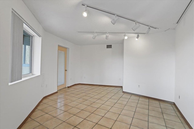 unfurnished room featuring rail lighting, baseboards, and visible vents