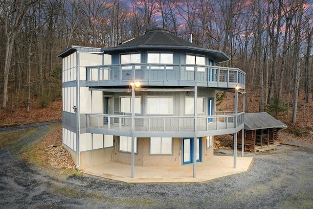 back of house featuring a balcony, board and batten siding, and a patio
