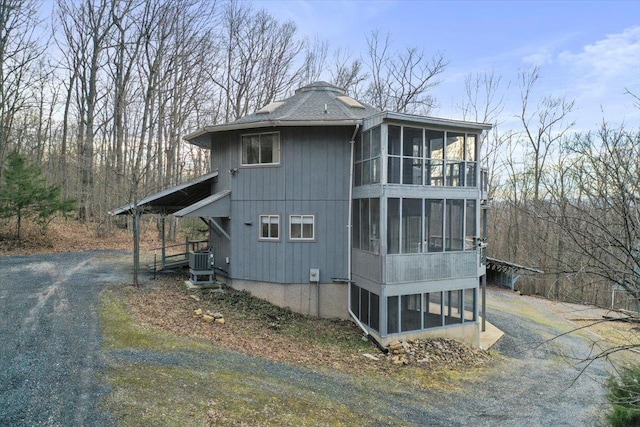 view of home's exterior with a sunroom, driveway, and cooling unit