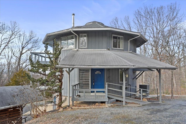 view of front facade with central AC unit, a shingled roof, and covered porch
