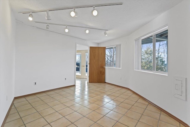 spare room featuring baseboards, rail lighting, and light tile patterned floors