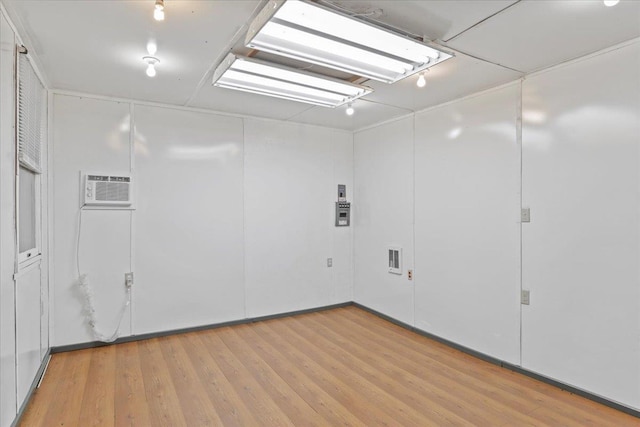 below grade area with light wood-style flooring and a wall mounted AC