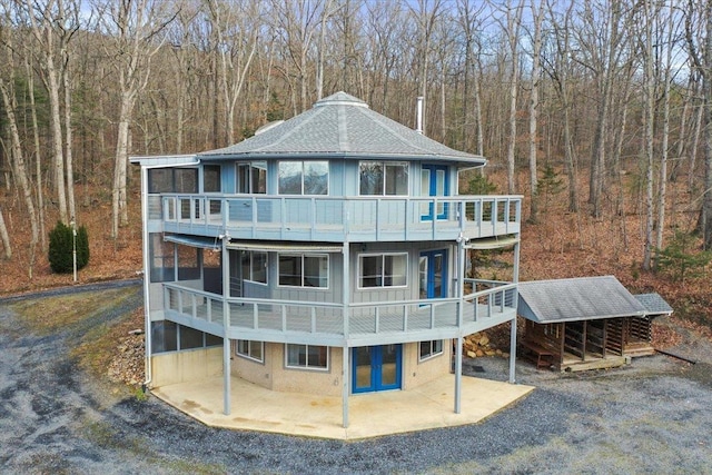 back of house featuring a wooded view, a patio area, and a balcony