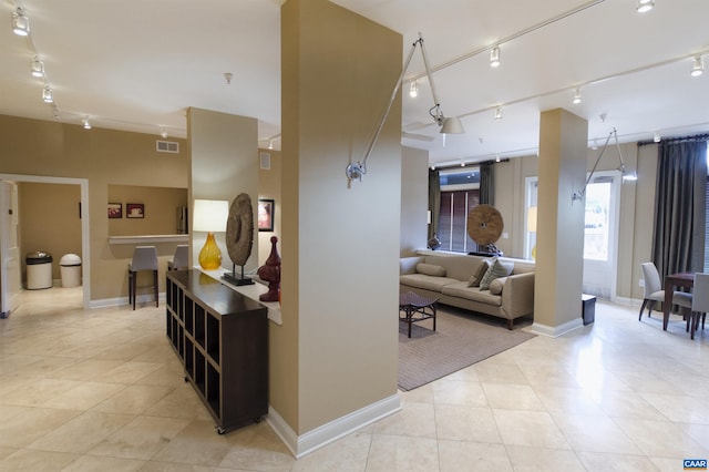 hallway with track lighting, light tile patterned floors, and baseboards