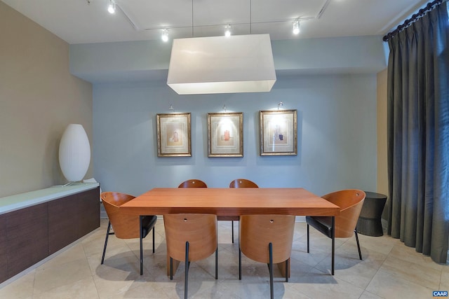 dining space with track lighting and light tile patterned flooring