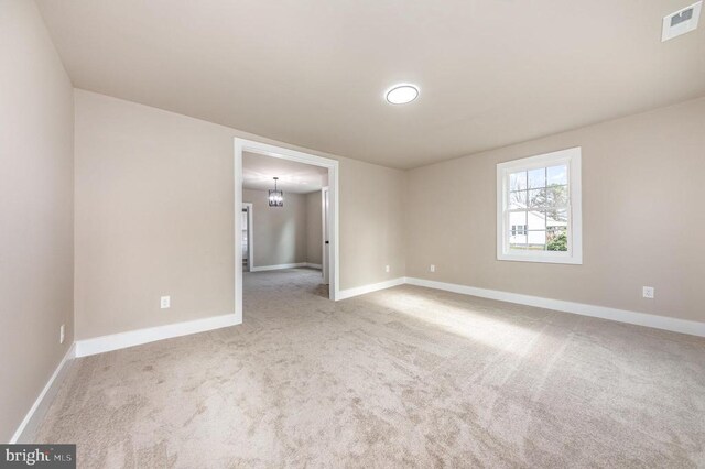 carpeted spare room with a notable chandelier