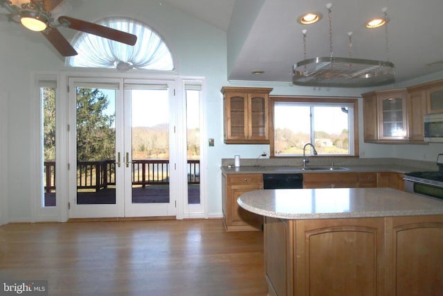 kitchen featuring a sink, appliances with stainless steel finishes, light wood finished floors, vaulted ceiling, and brown cabinets