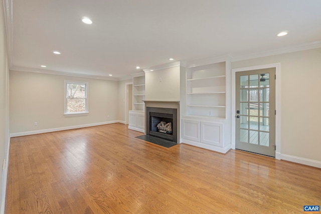 unfurnished living room featuring baseboards, crown molding, a fireplace with flush hearth, recessed lighting, and wood finished floors