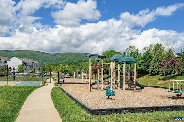 community play area featuring a mountain view and fence