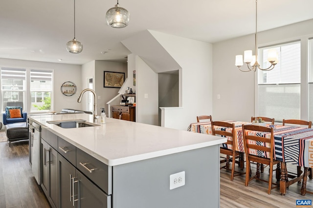 kitchen featuring a sink, a chandelier, wood finished floors, light countertops, and open floor plan