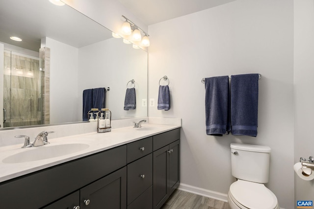 full bath featuring toilet, baseboards, a tile shower, wood finished floors, and double vanity