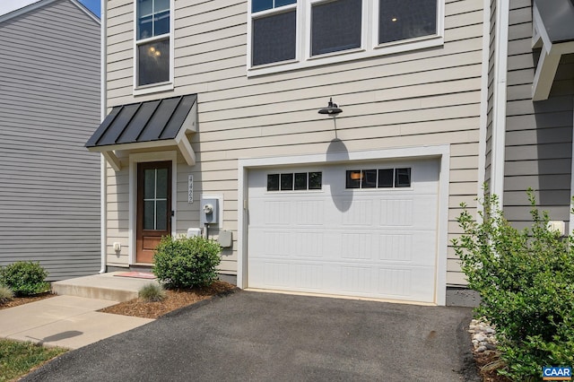 entrance to property with a garage, a standing seam roof, metal roof, and driveway