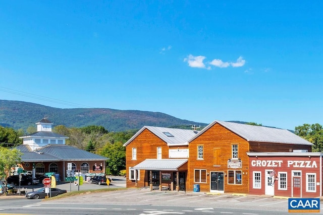 view of building exterior with a mountain view and uncovered parking