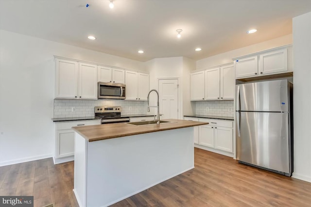 kitchen with stainless steel appliances, a sink, dark countertops, decorative backsplash, and white cabinets