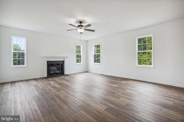 unfurnished living room featuring plenty of natural light, a ceiling fan, and dark wood-type flooring