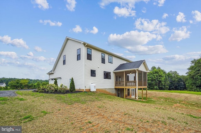rear view of house featuring a sunroom and a lawn