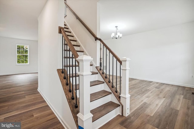 stairs featuring wood finished floors, a chandelier, and baseboards