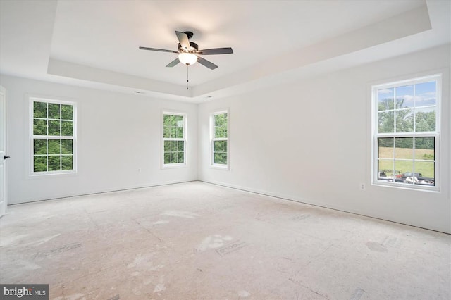 unfurnished room featuring a tray ceiling, healthy amount of natural light, and ceiling fan