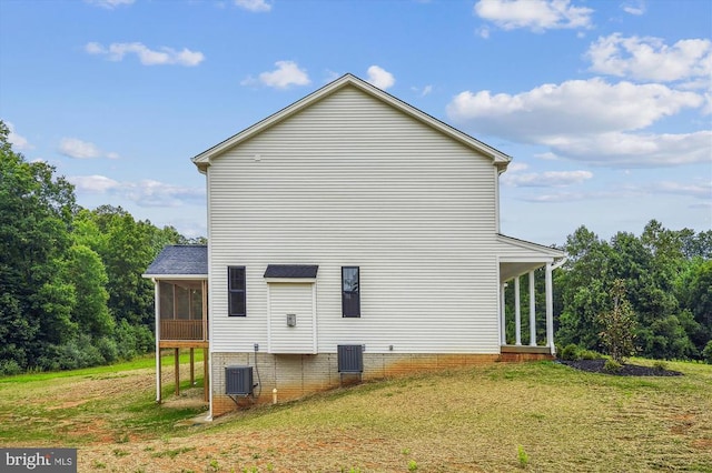 view of side of home featuring a sunroom, a lawn, and central AC unit