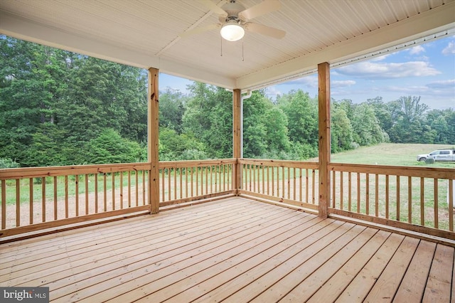 wooden deck with a ceiling fan and view of scattered trees