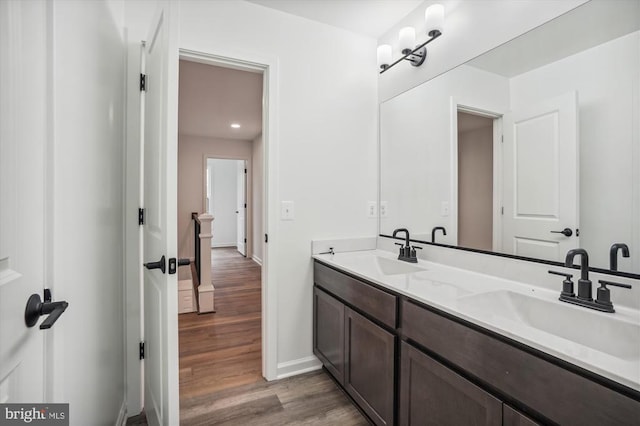 bathroom featuring wood finished floors, baseboards, and double vanity
