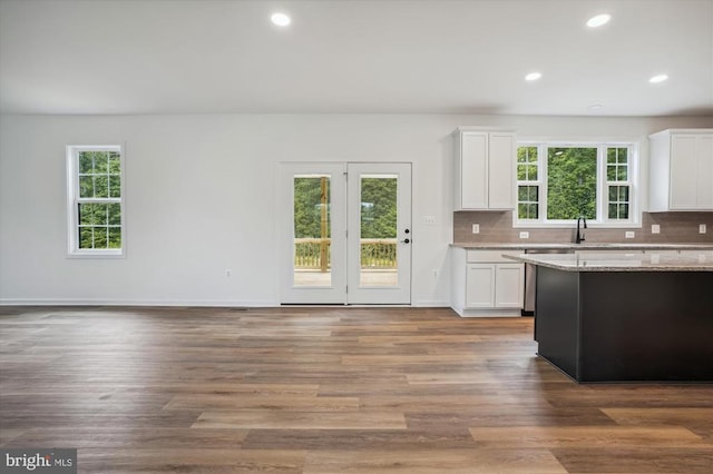 kitchen featuring stainless steel dishwasher, white cabinetry, decorative backsplash, light stone countertops, and recessed lighting
