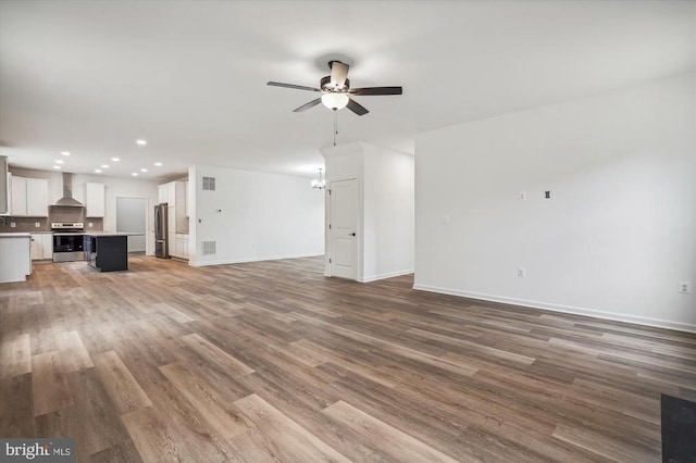 unfurnished living room featuring a ceiling fan, recessed lighting, baseboards, and wood finished floors