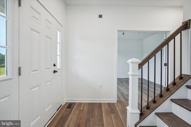 foyer entrance featuring dark wood-type flooring, baseboards, and stairs