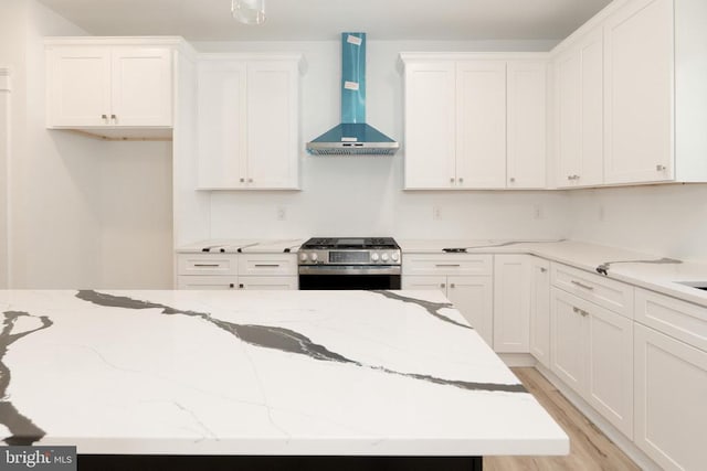 29 Dove Ct, Bumpass, VA 23024 - kitchen with wall chimney range hood, stainless steel range with gas cooktop, white cabinetry, light stone countertops, and light wood-style floors