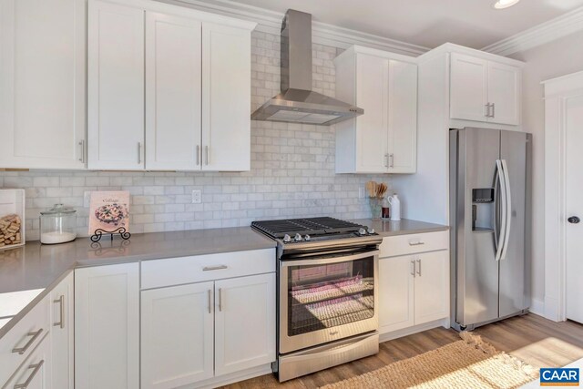 kitchen featuring stainless steel appliances, wall chimney exhaust hood, light countertops, white cabinets, and light wood-style flooring