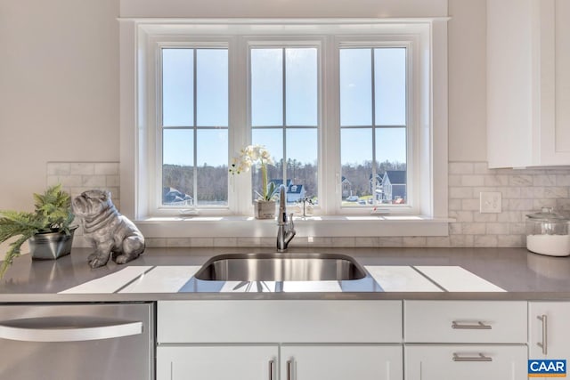 kitchen featuring dishwasher, a sink, white cabinets, tasteful backsplash, and light countertops