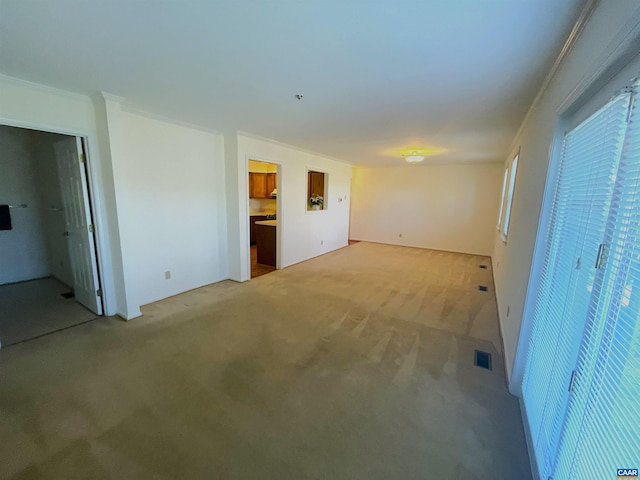 empty room featuring ornamental molding, visible vents, and light colored carpet