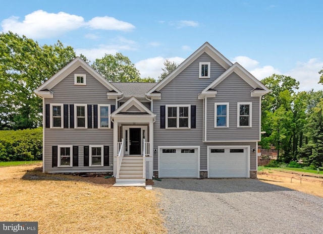 bi-level home with gravel driveway and an attached garage