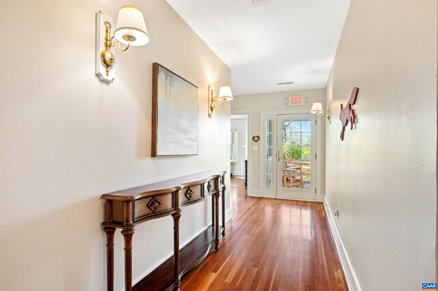 hallway with baseboards, visible vents, and wood finished floors