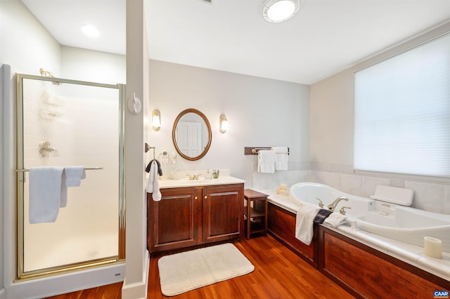 full bath featuring a garden tub, vanity, wood finished floors, and a stall shower